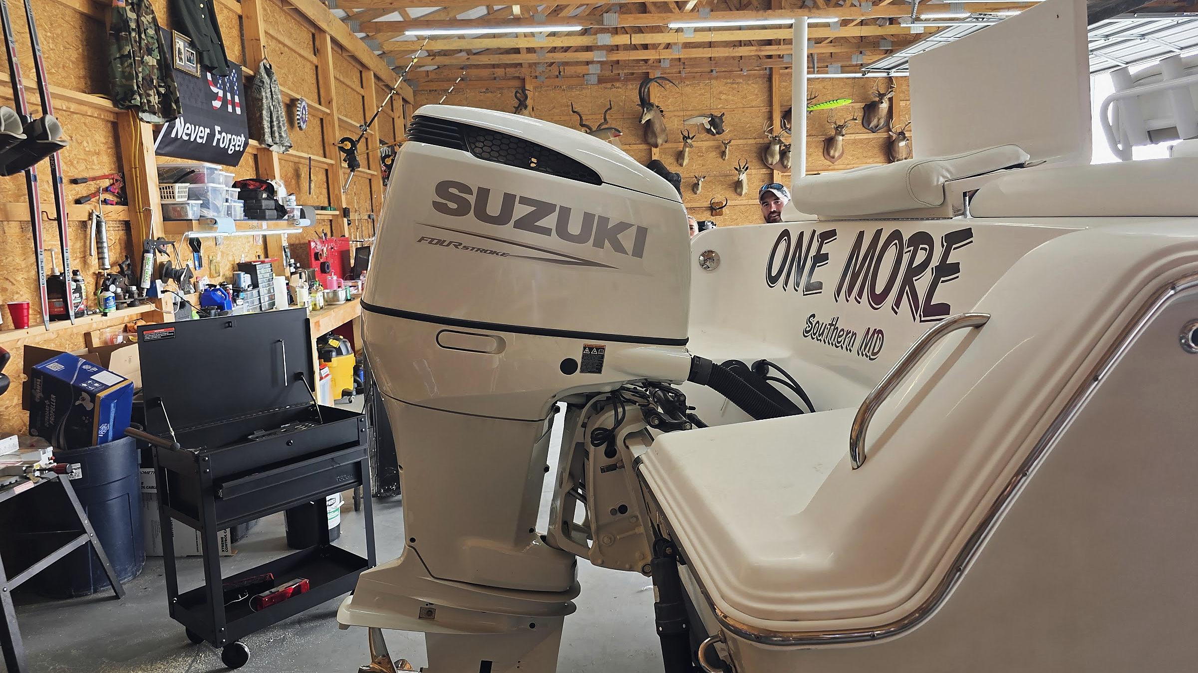 A Suzuki outboard on the boat One More, inside the Patriot Marine shop, the Never Forget flag on the wall