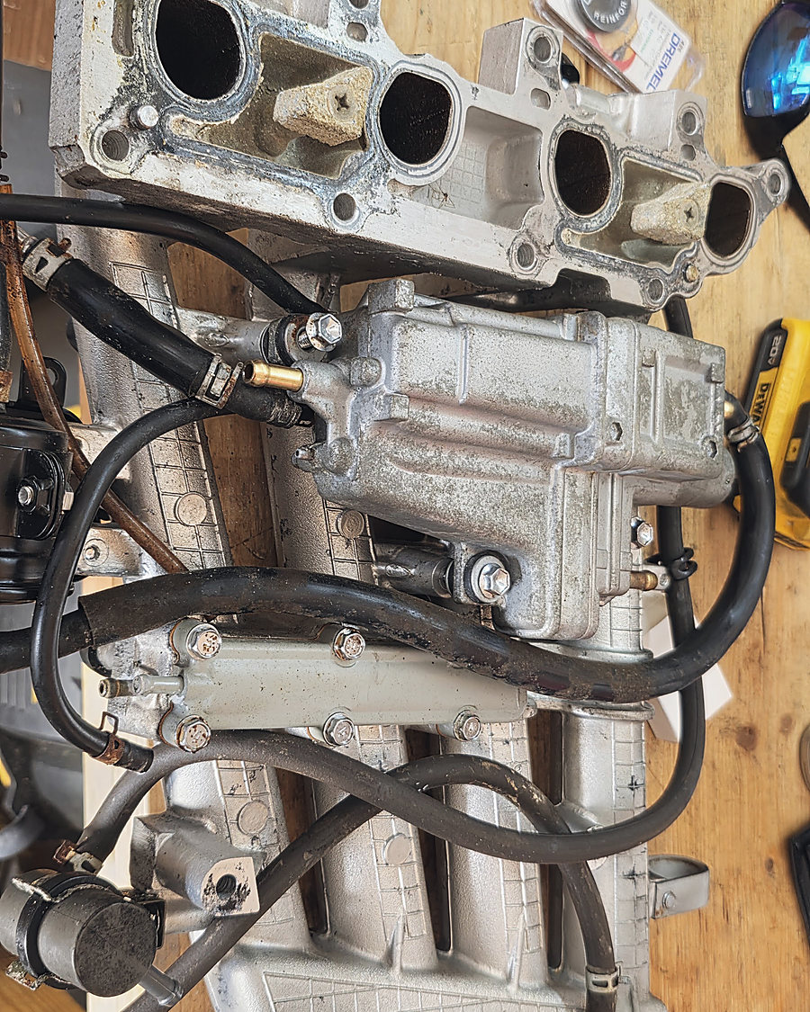 An intake manifold and fuel lines on the bench, mid-rebuild