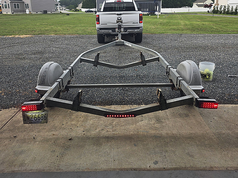 A boat trailer and truck on the gravel lot, seen from behind