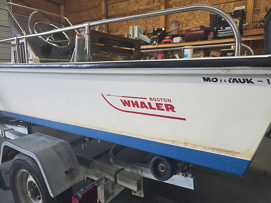 The Boston Whaler badge on the hull, the boat on her trailer in the shop